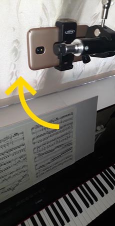 mobile phone mounted over a piano keyboard and tilted away