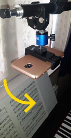 mobile phone mounted over a piano keyboard and tilted to face down over keys